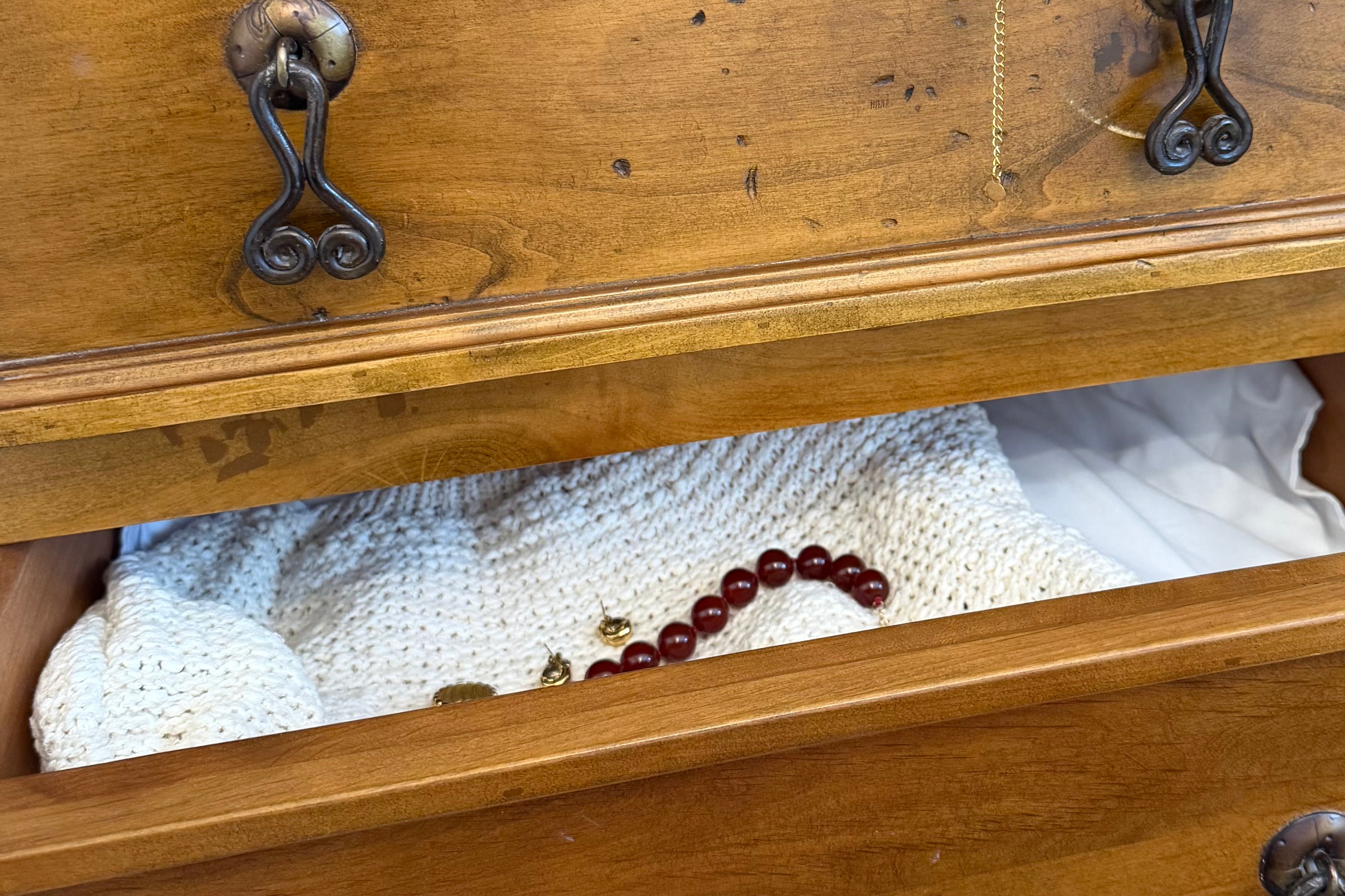 Everyday jewelry pieces styled inside a wooden drawer with gold earrings and a red agate necklace.  