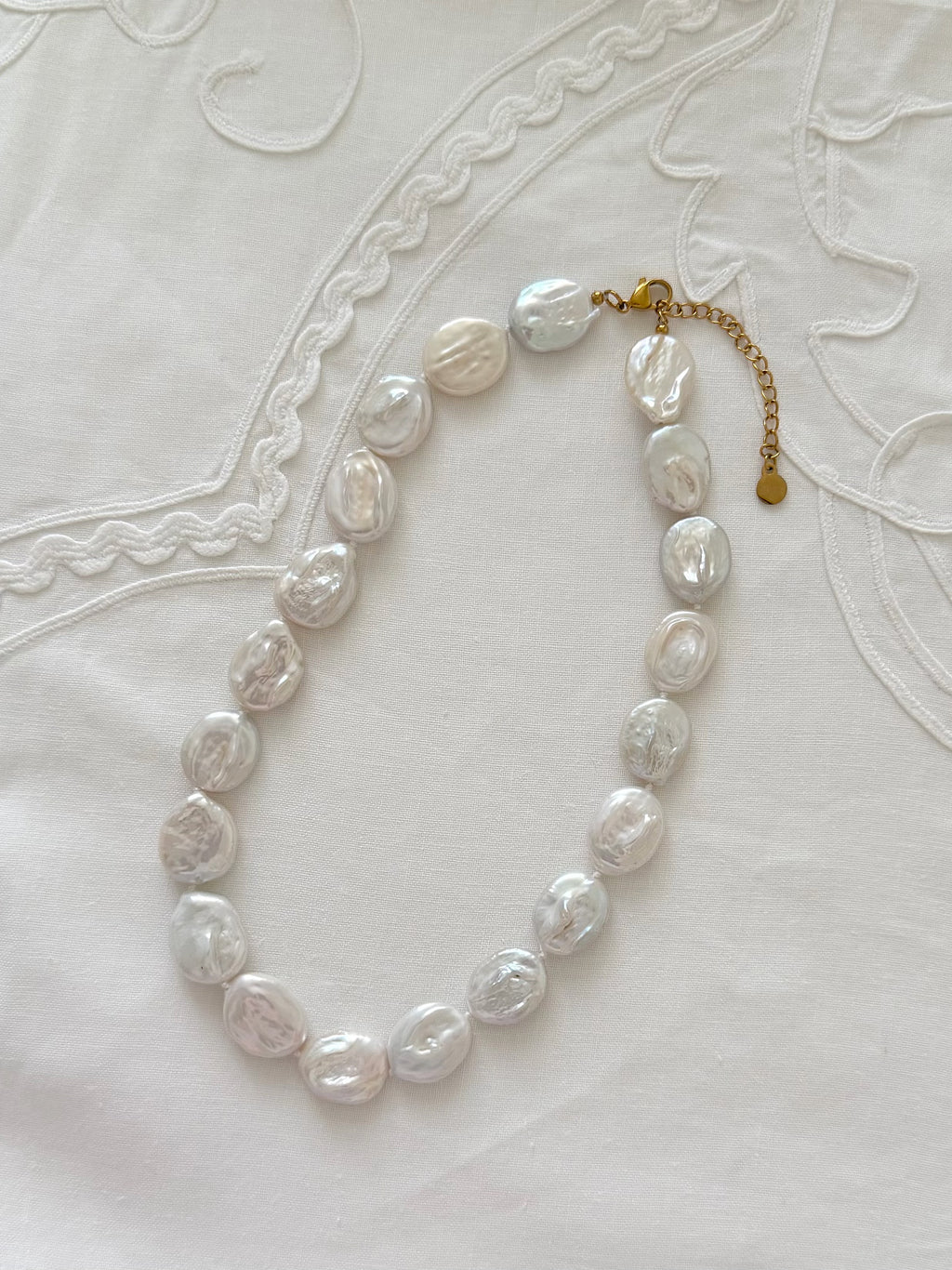 Button pearl necklace flat lay with oversized freshwater pearl details