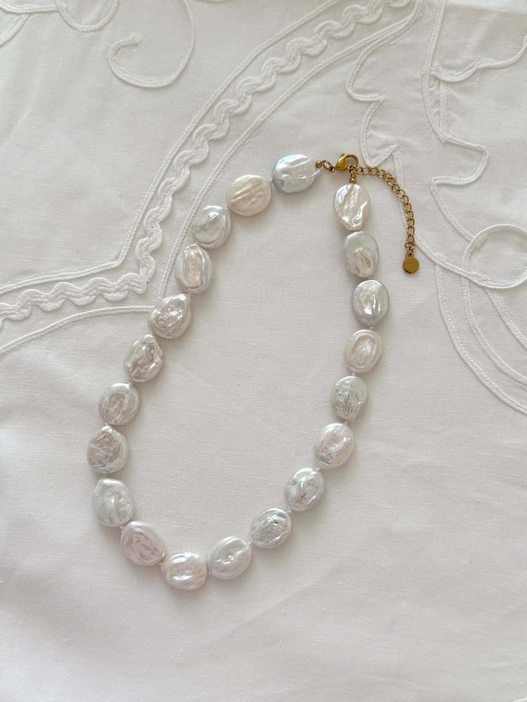 Button pearl necklace flat lay with oversized freshwater pearl details