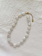 Button pearl necklace flat lay with oversized freshwater pearl details