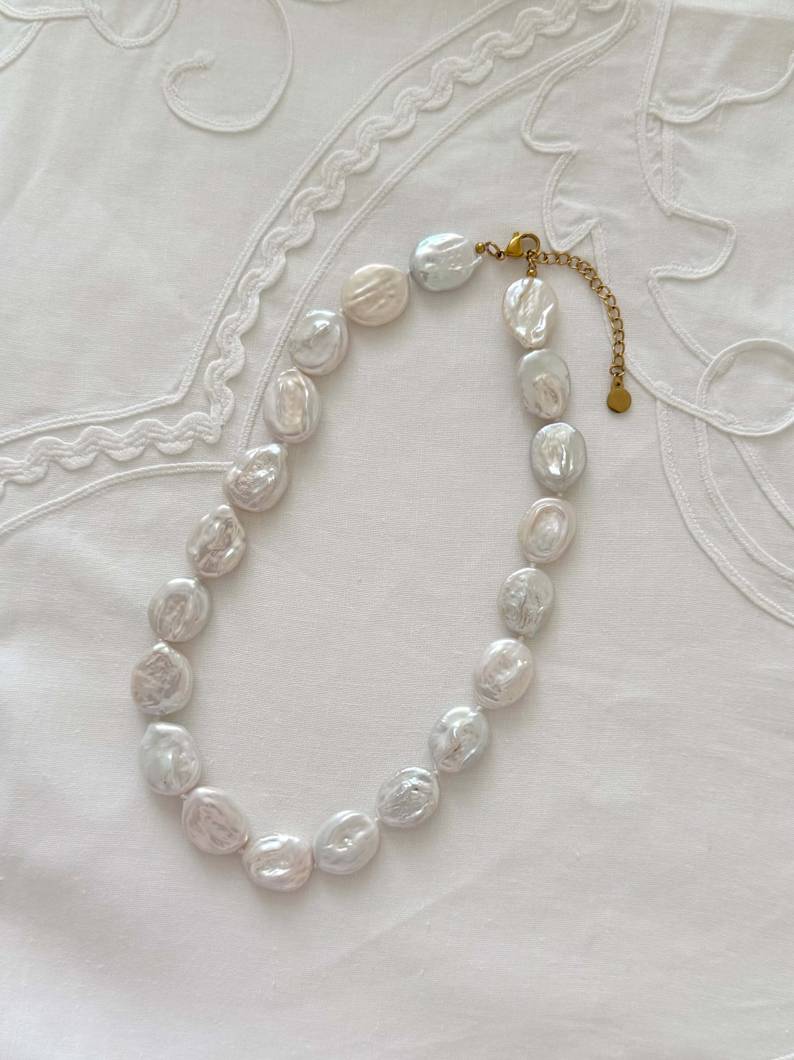 Button pearl necklace flat lay with oversized freshwater pearl details
