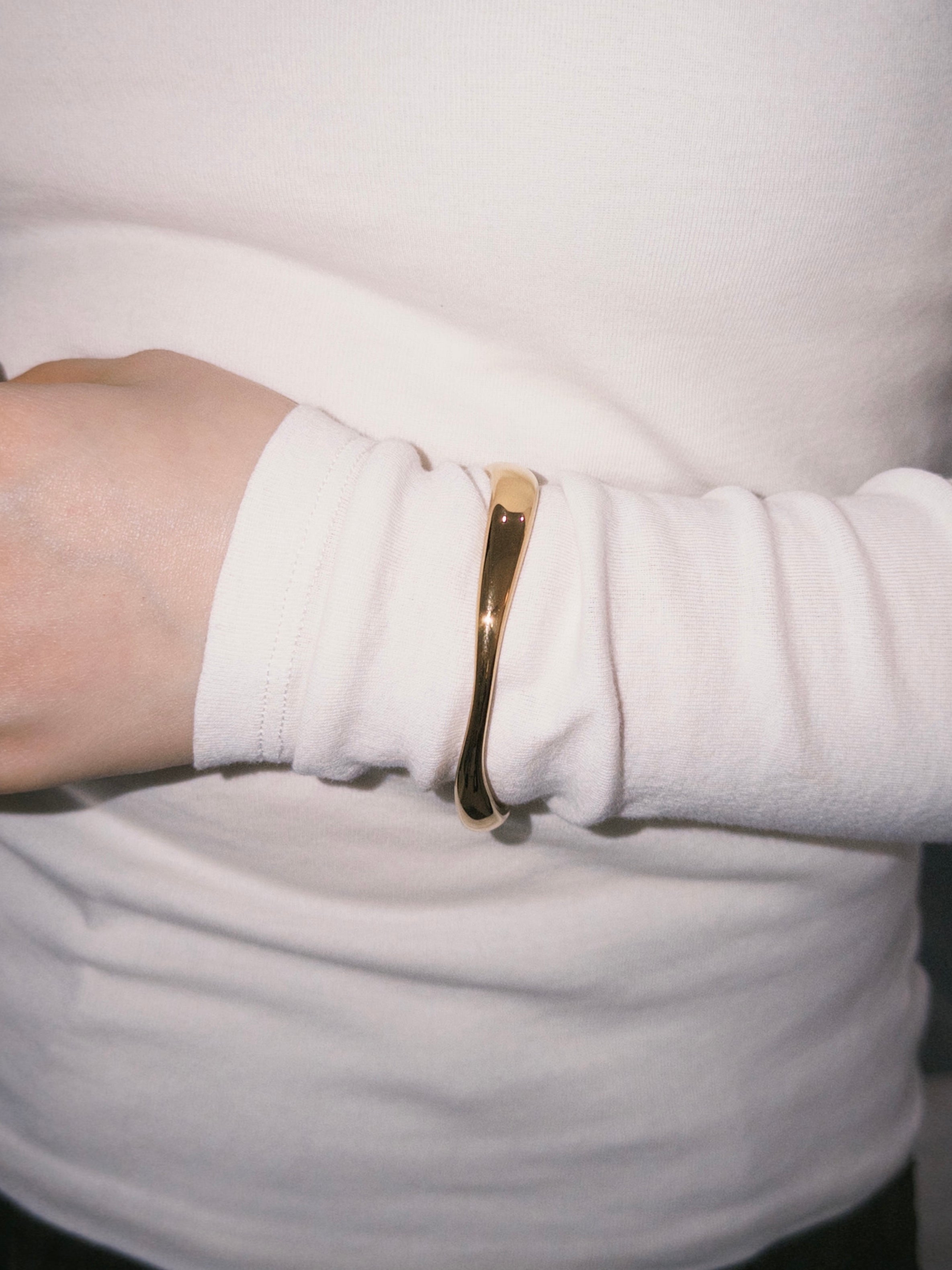 Gold cuff bracelet styled with soft white long sleeve outfit