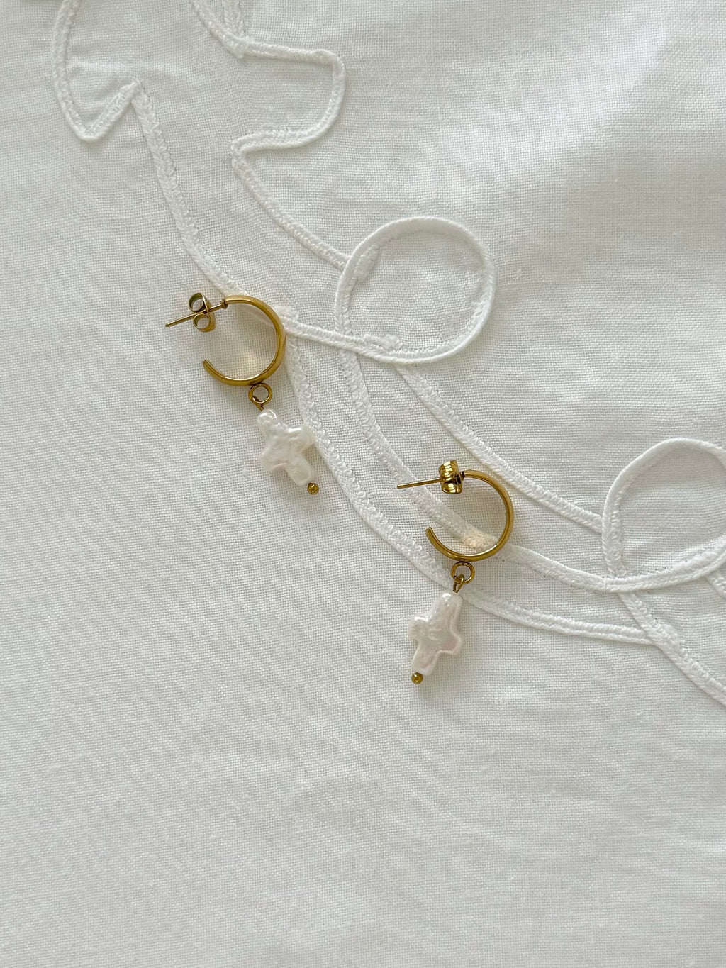 Freshwater pearl hoop earrings displayed on soft neutral fabric