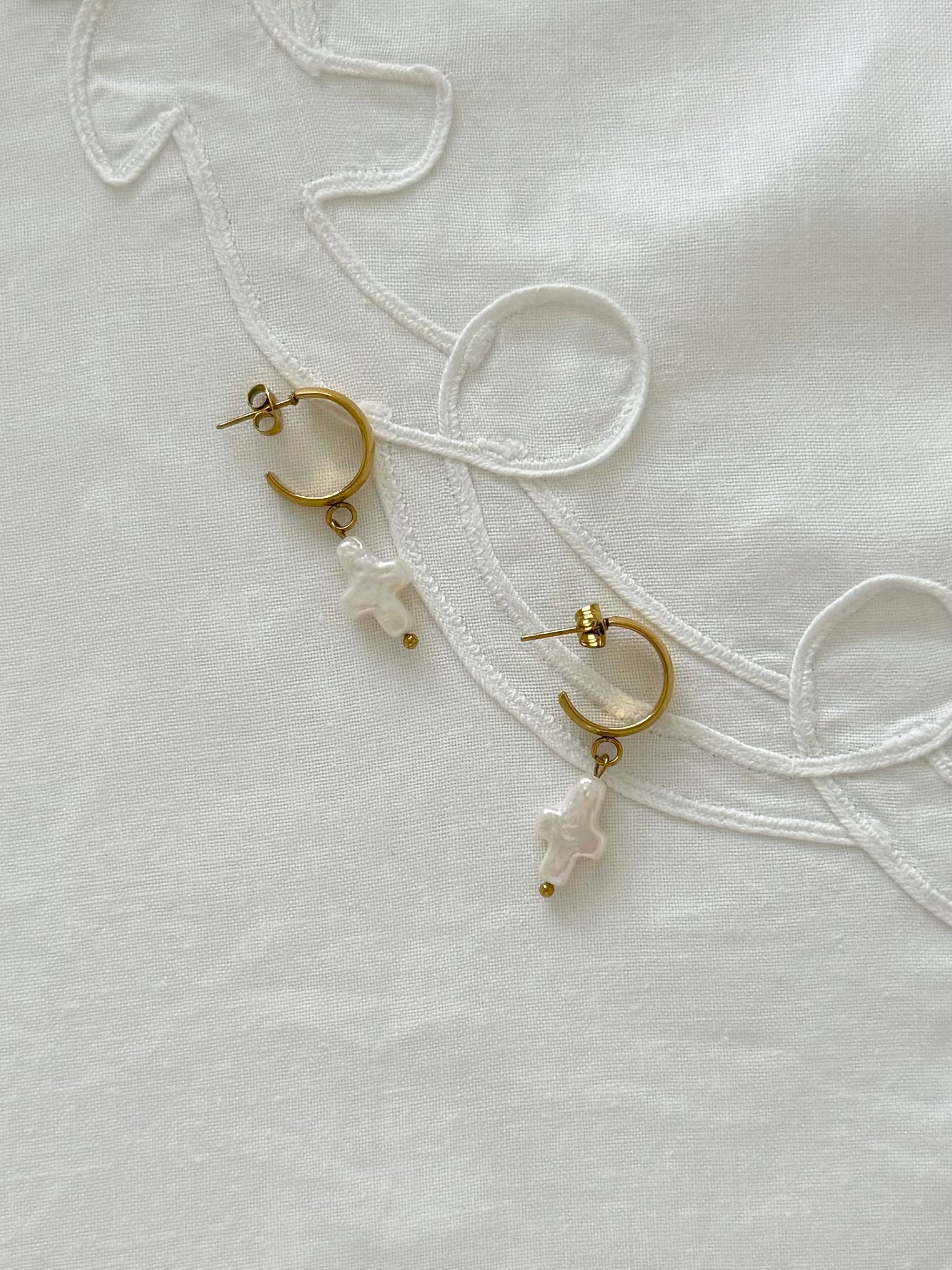 Freshwater pearl hoop earrings displayed on soft neutral fabric