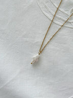 Freshwater pearl cross necklace displayed on soft neutral fabric