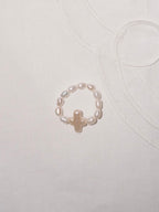 Pearl cross ring flat lay with minimalist everyday styling