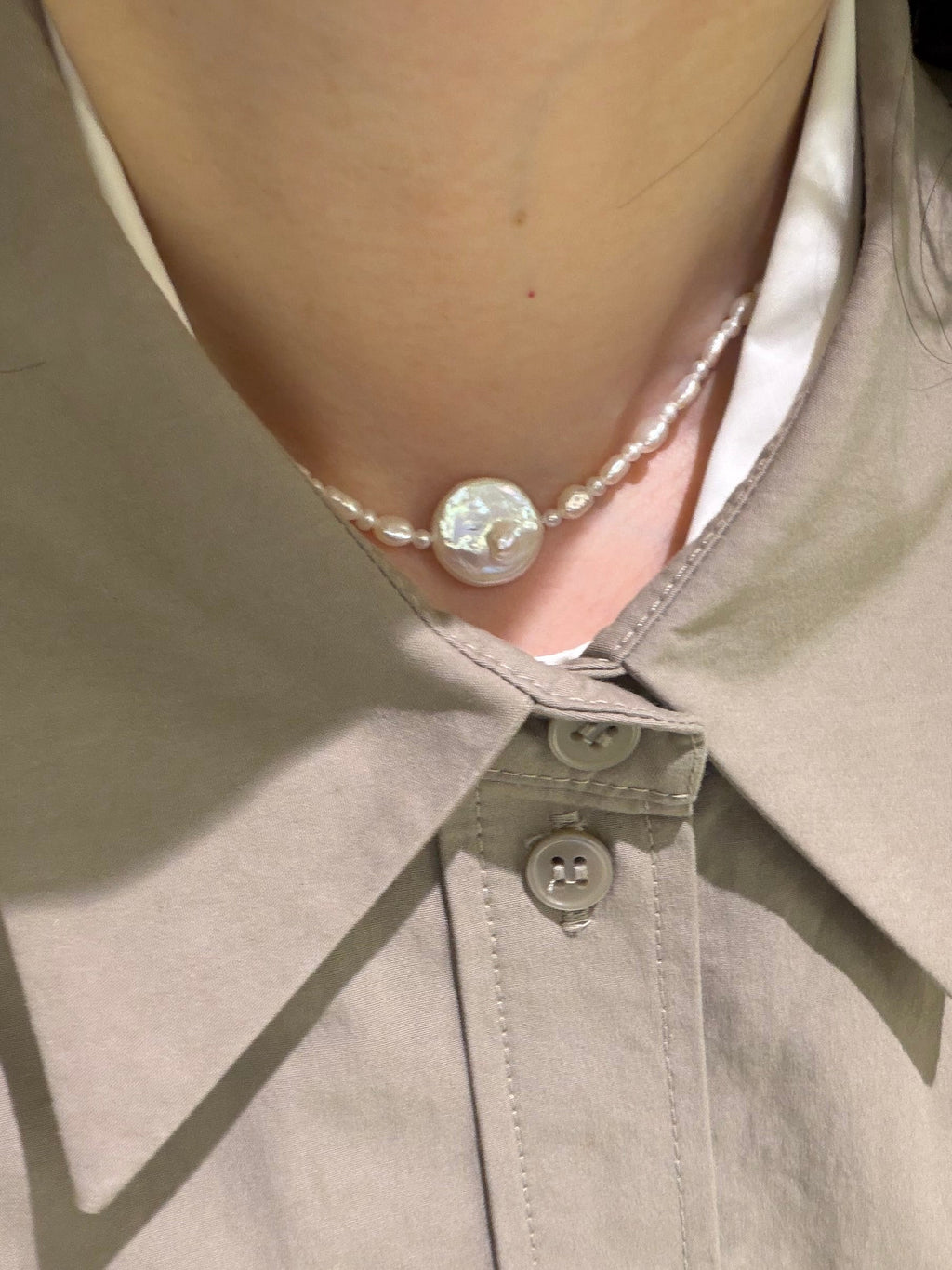 Minimal pearl choker paired with an open collar shirt and soft neutral tones