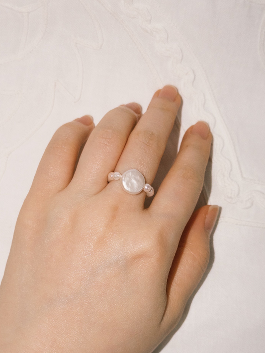 Statement pearl ring styled softly in natural warm lighting