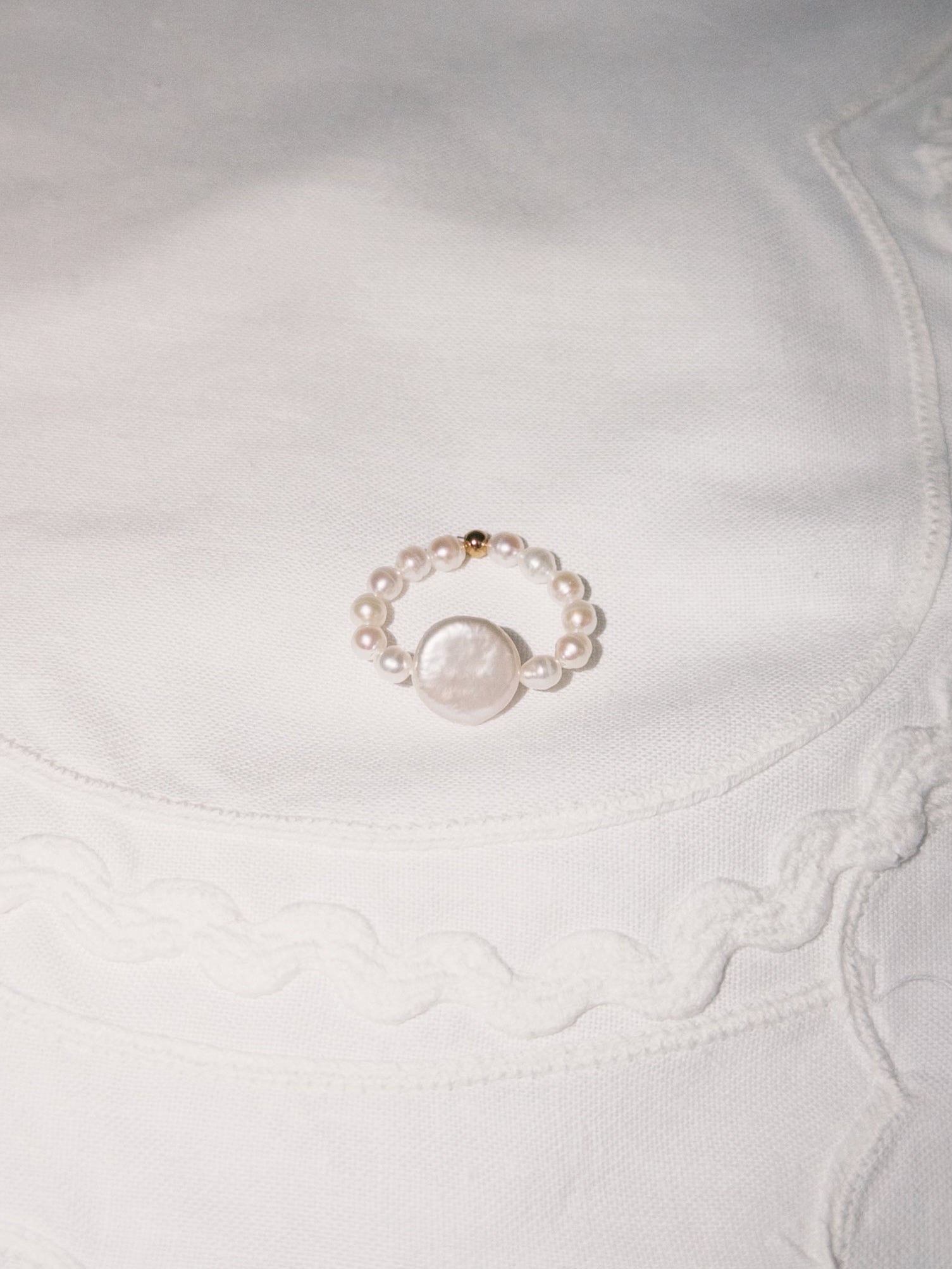 Freshwater pearl ring displayed on soft neutral fabric with minimal styling