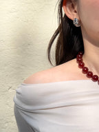 Red agate necklace styled with sculptural silver earrings in natural sunlight