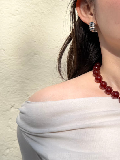 Red agate necklace styled with sculptural silver earrings in natural sunlight