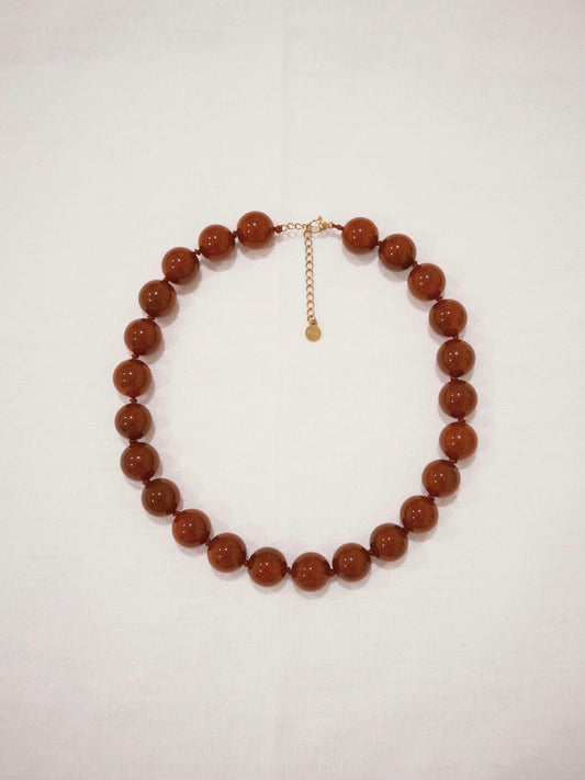 Red agate bead necklace flat lay with bold natural stone details