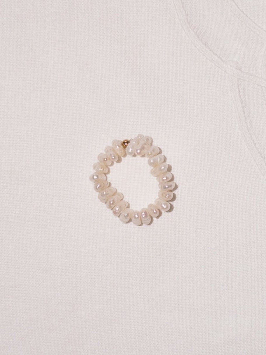 Pearl cross ring flat lay with soft neutral styling