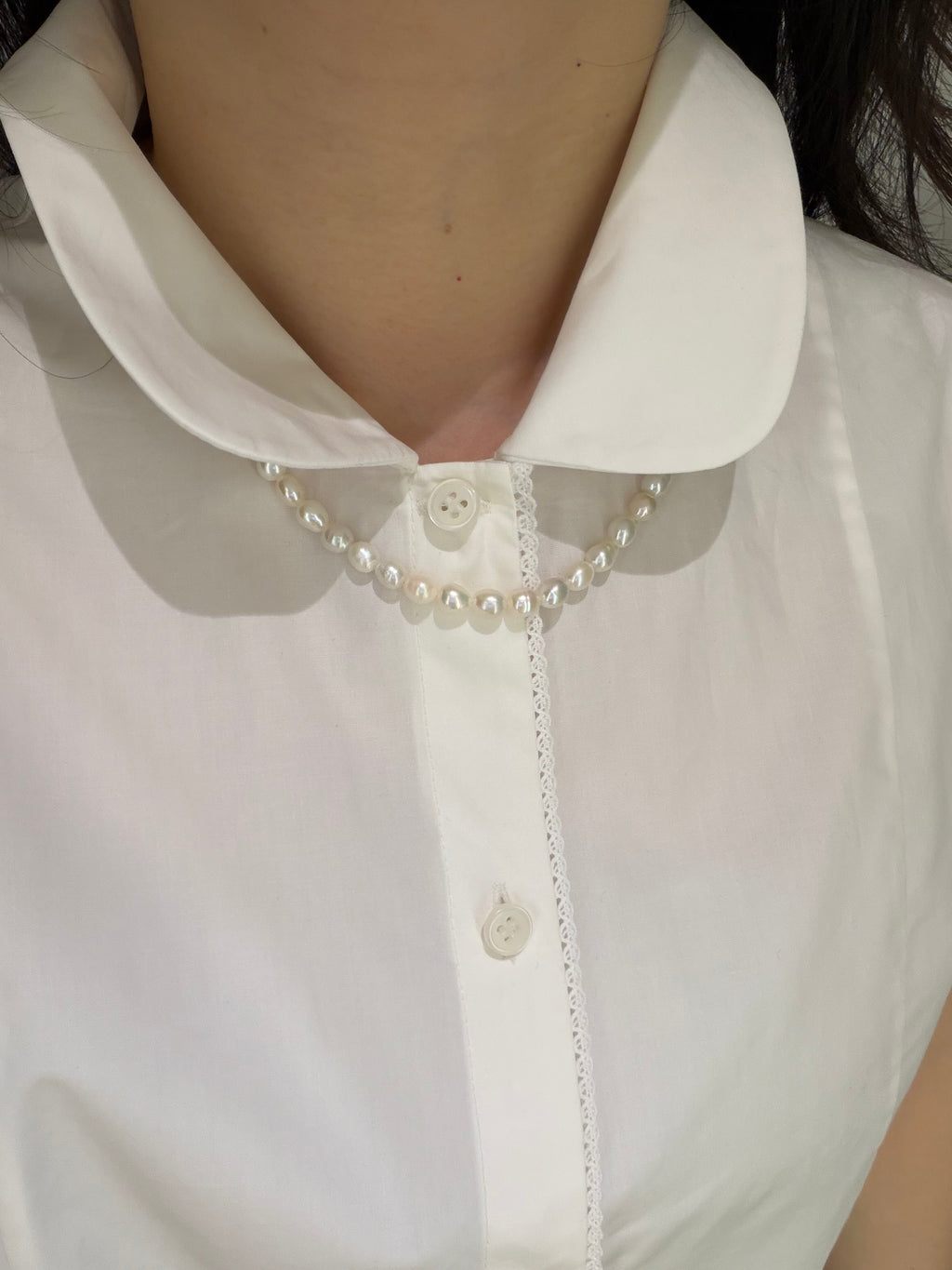 Minimal pearl necklace paired with a white collar shirt for a clean everyday look