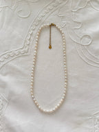 Freshwater pearl necklace displayed on soft neutral fabric with minimal styling