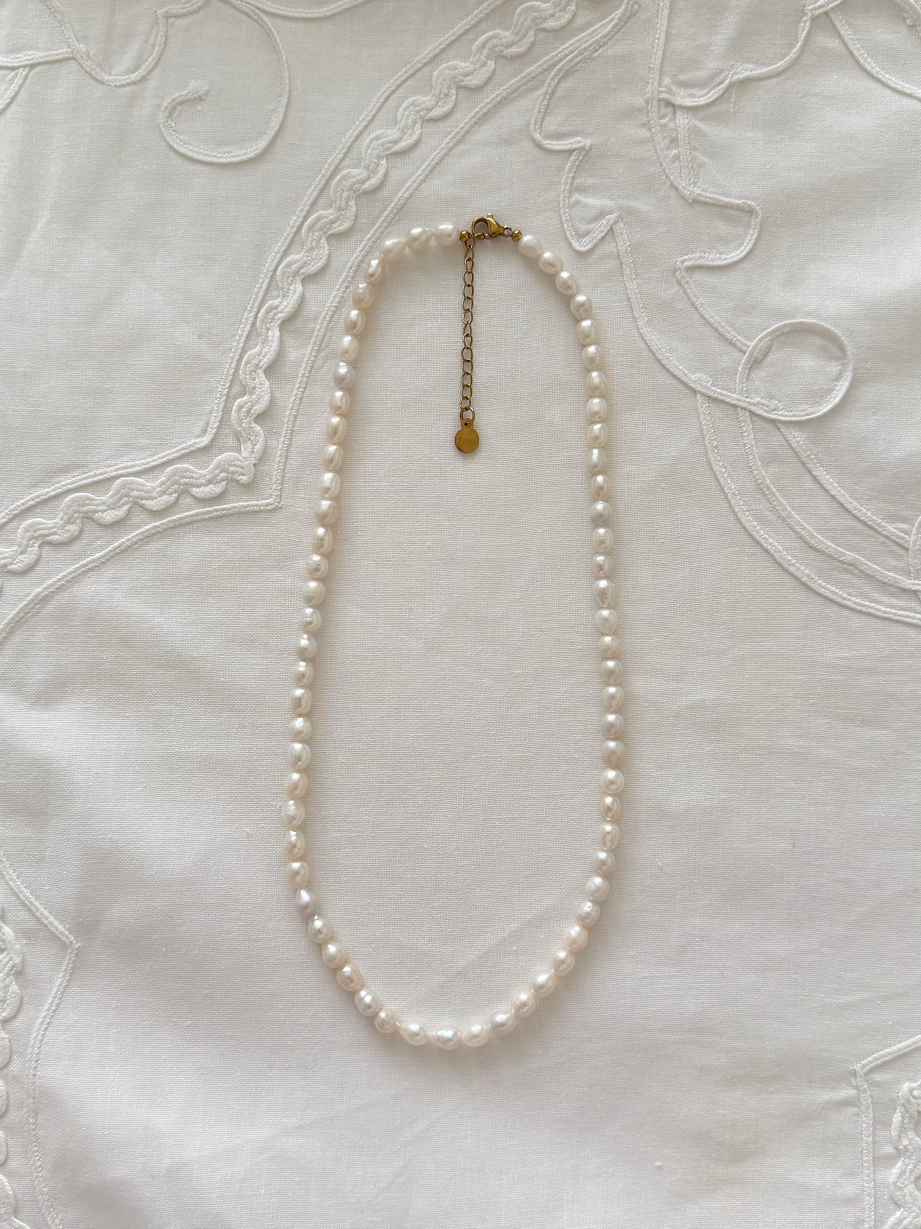 Freshwater pearl necklace displayed on soft neutral fabric with minimal styling