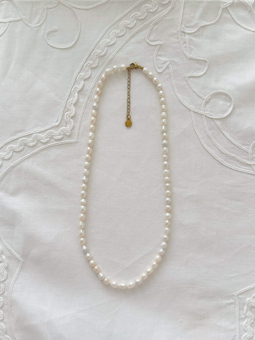 Freshwater pearl necklace displayed on soft neutral fabric with minimal 