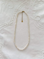 Freshwater pearl necklace displayed on soft neutral fabric with minimal 