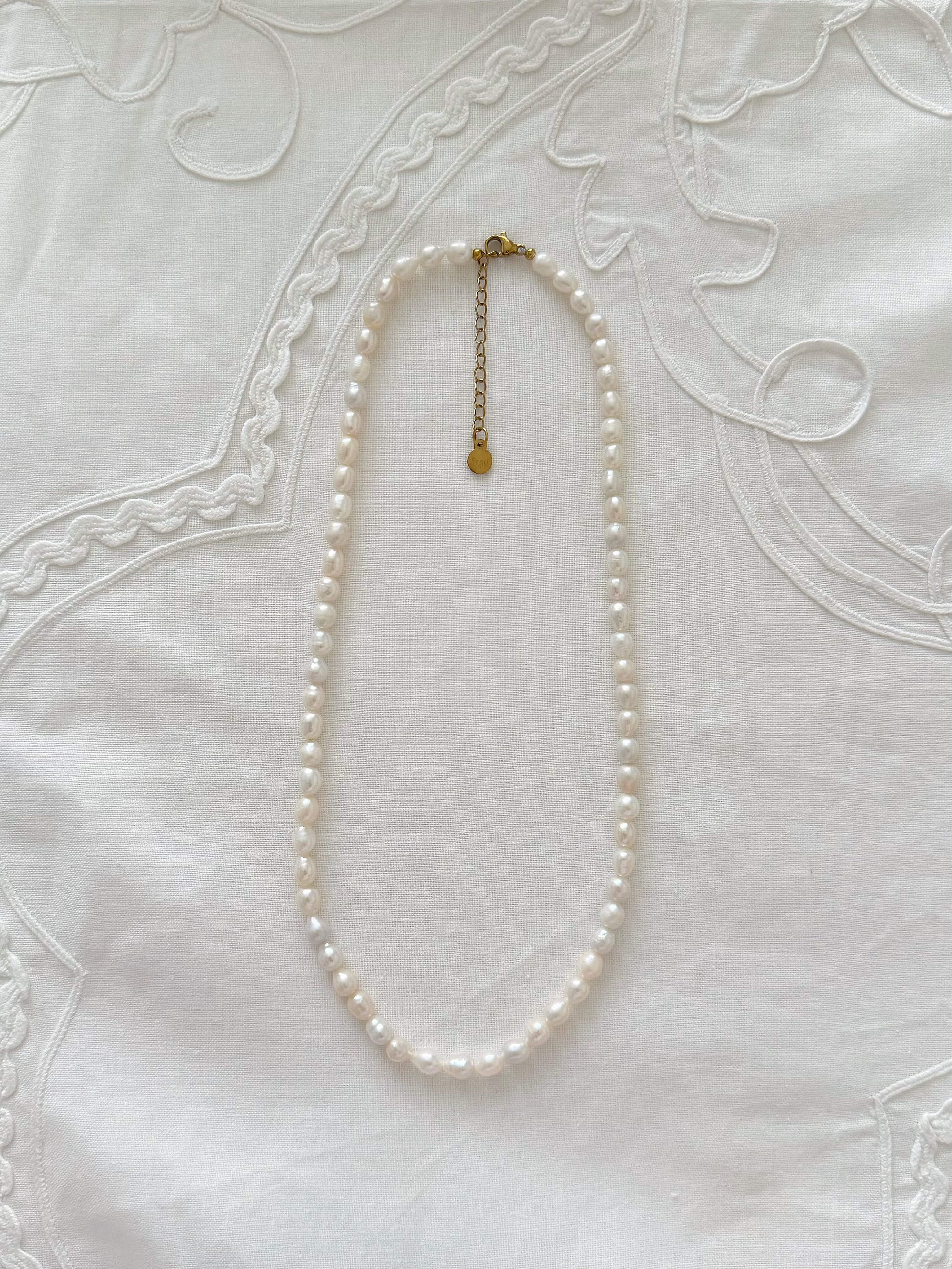 Freshwater pearl necklace displayed on soft neutral fabric with minimal 