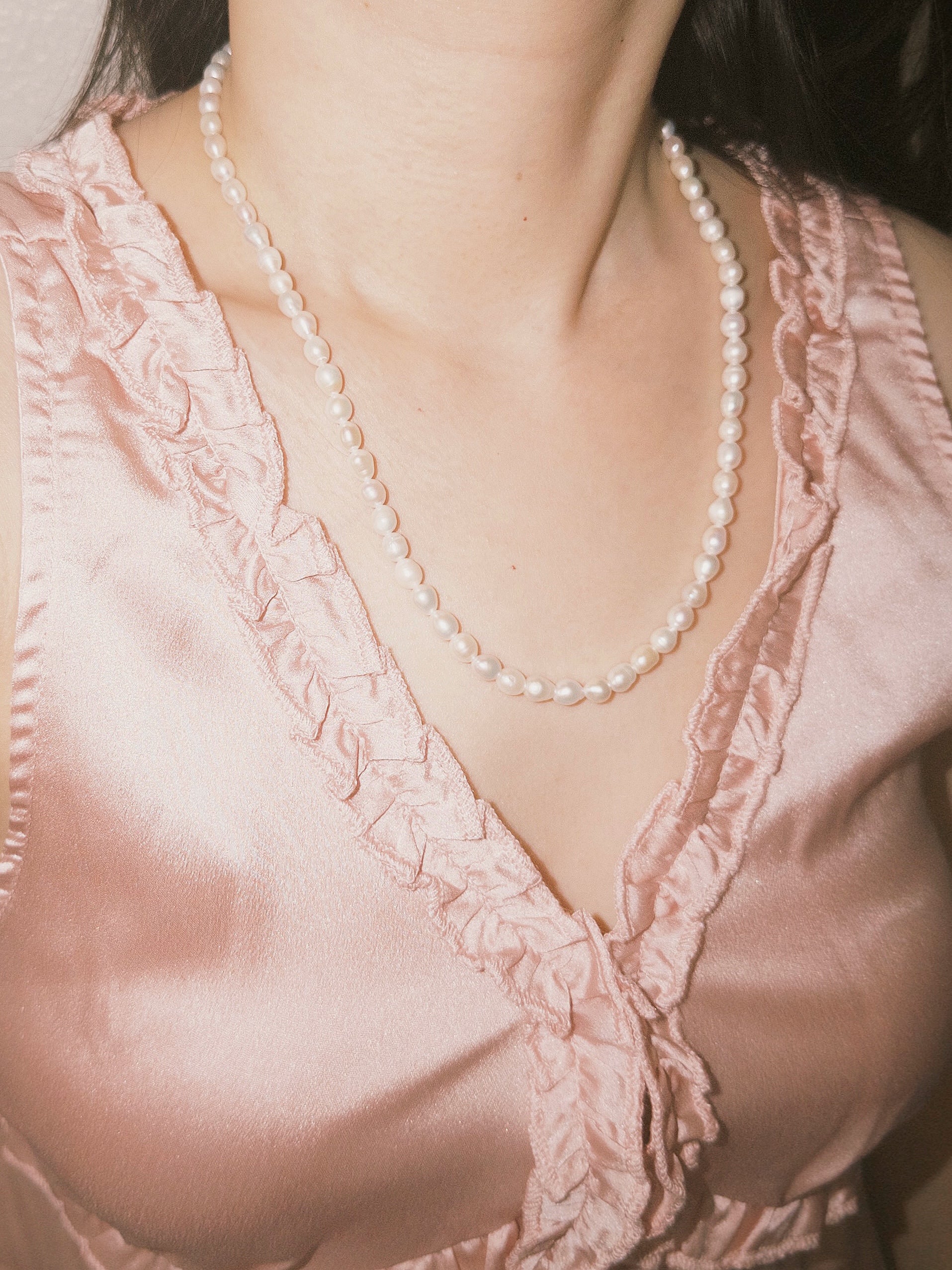Everyday pearl necklace paired with soft pink textures and natural styling