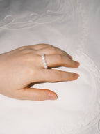 Minimal pearl ring styled softly in natural lighting