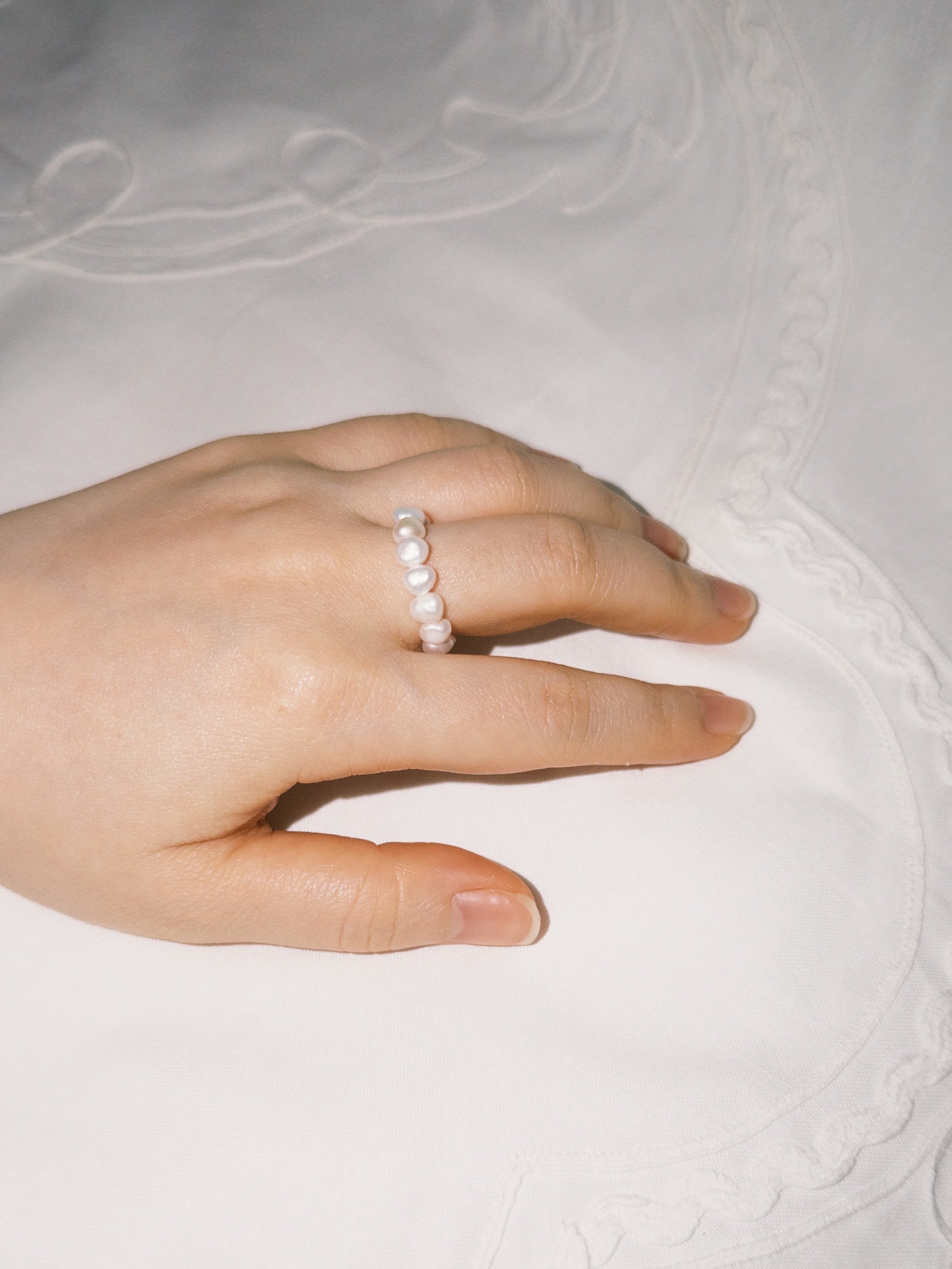 Minimal pearl ring styled softly in natural lighting
