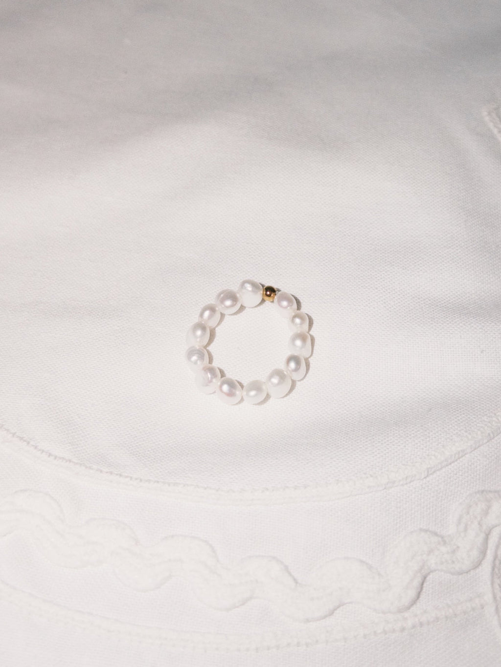 Minimal pearl ring displayed on soft neutral fabric