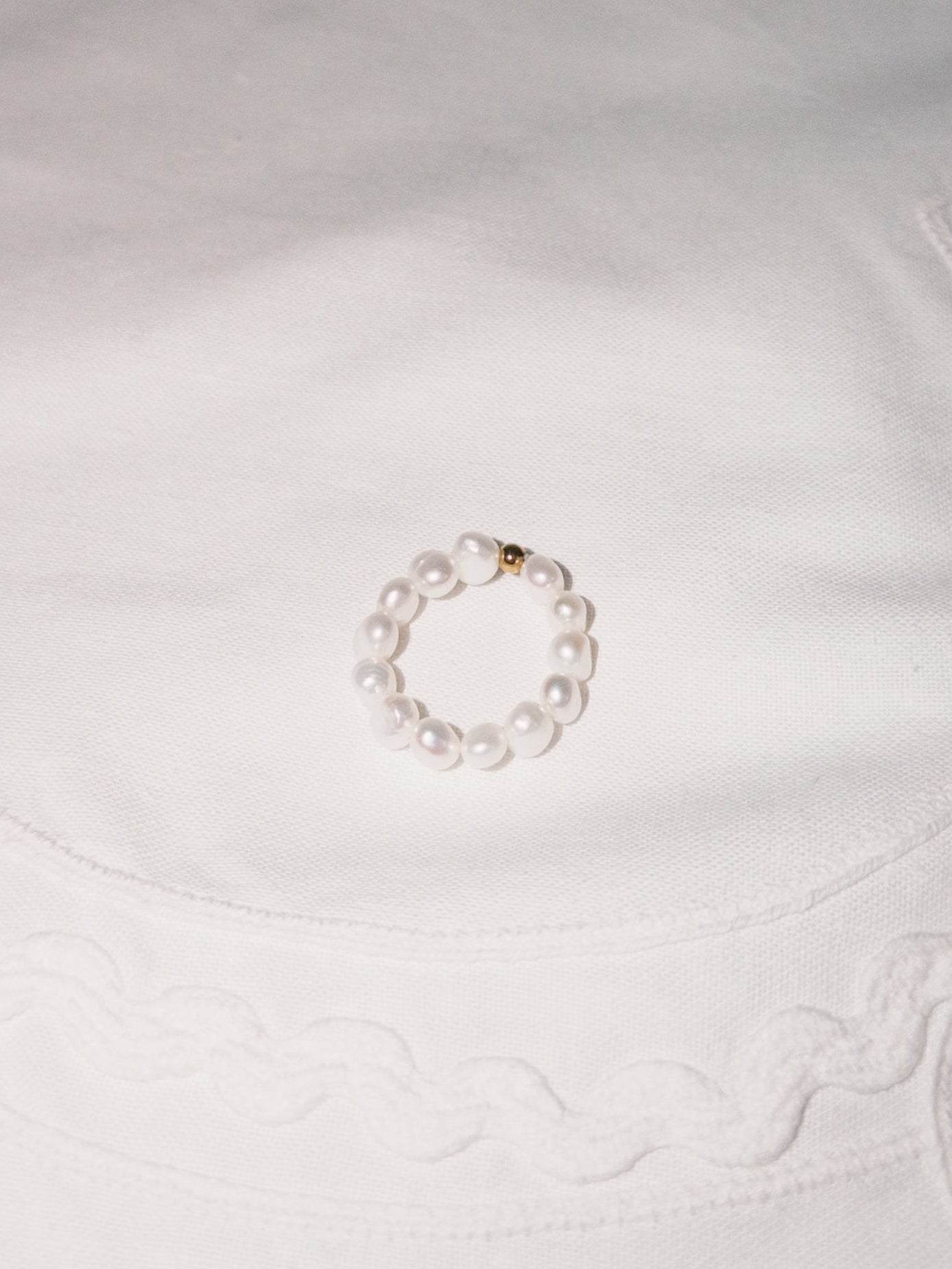 Minimal pearl ring displayed on soft neutral fabric