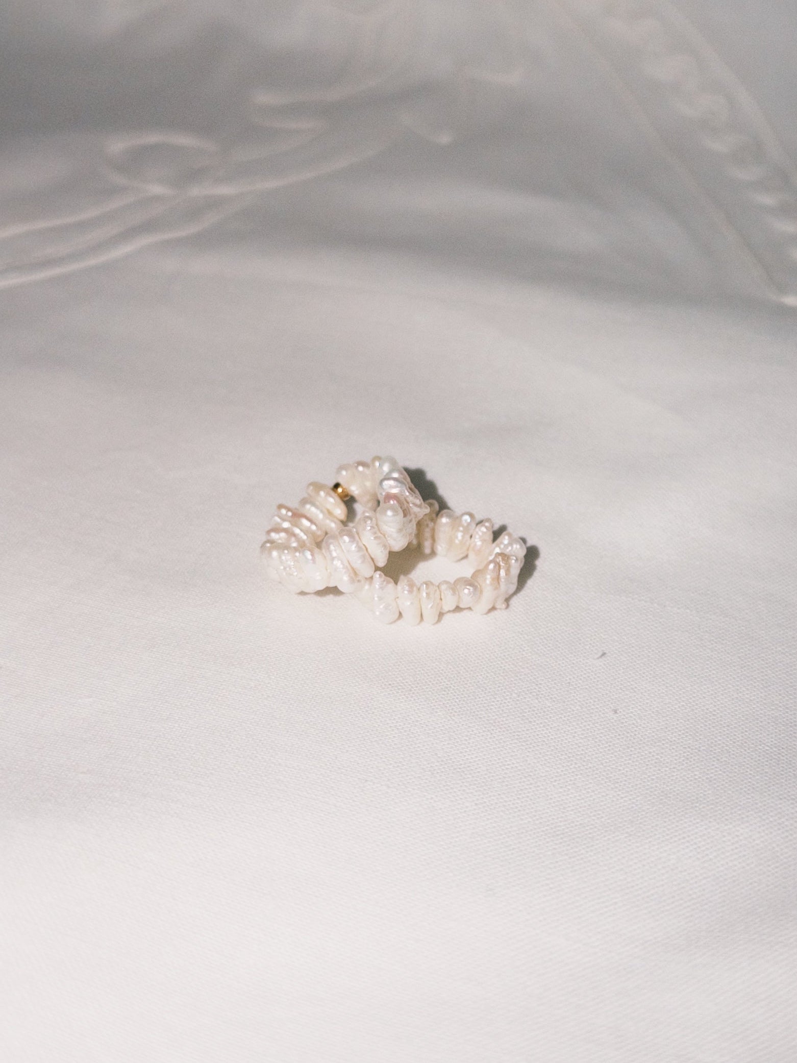 Stacked pearl rings arranged casually in soft natural light